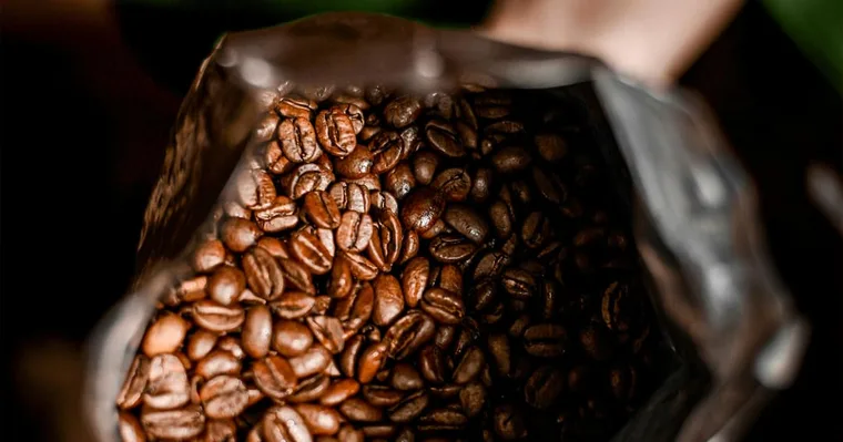 Freshly roasted coffee beans inside an open Kimor bag